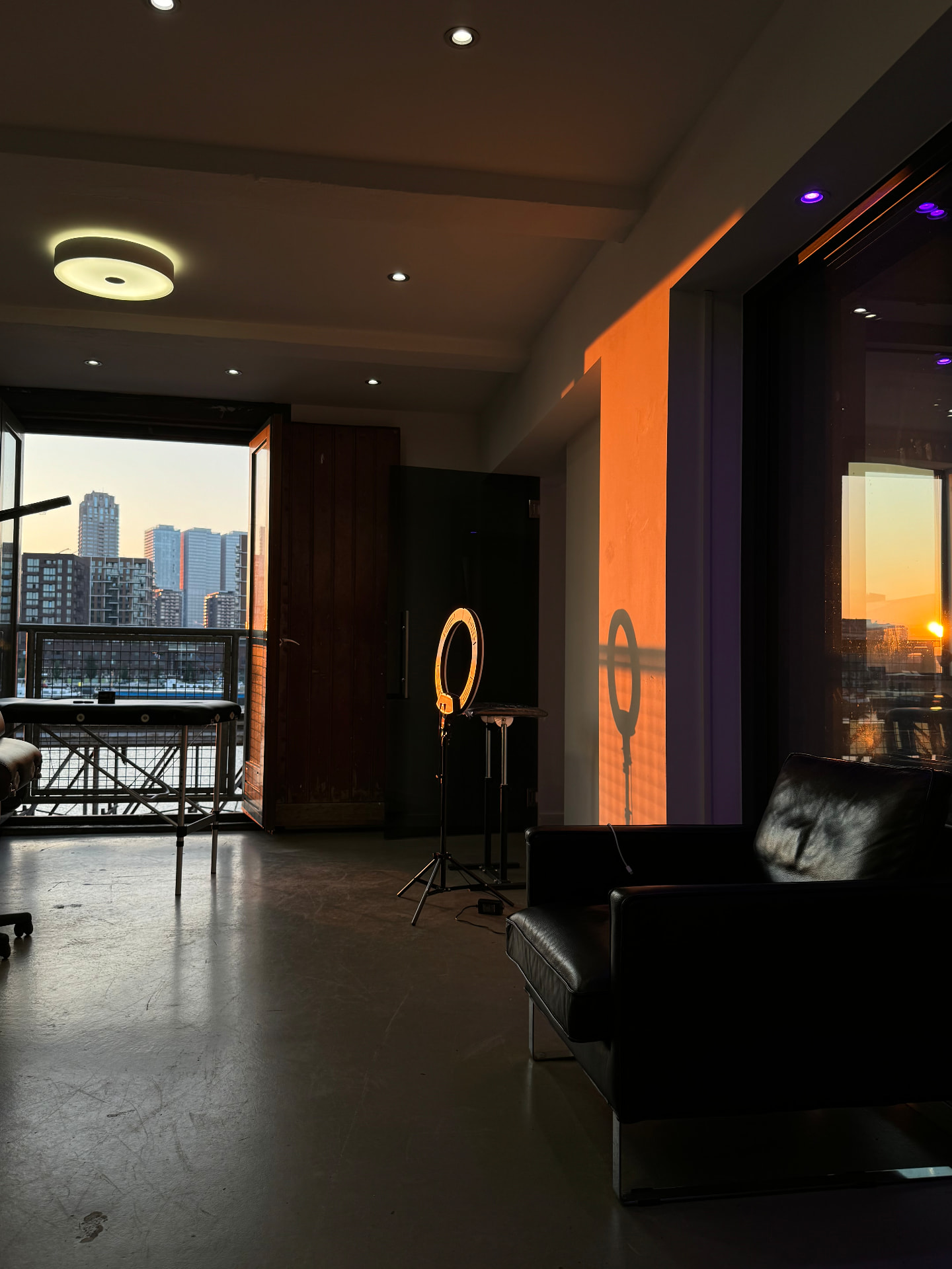 Tattoo studio interior at sunset with ring light and city skyline