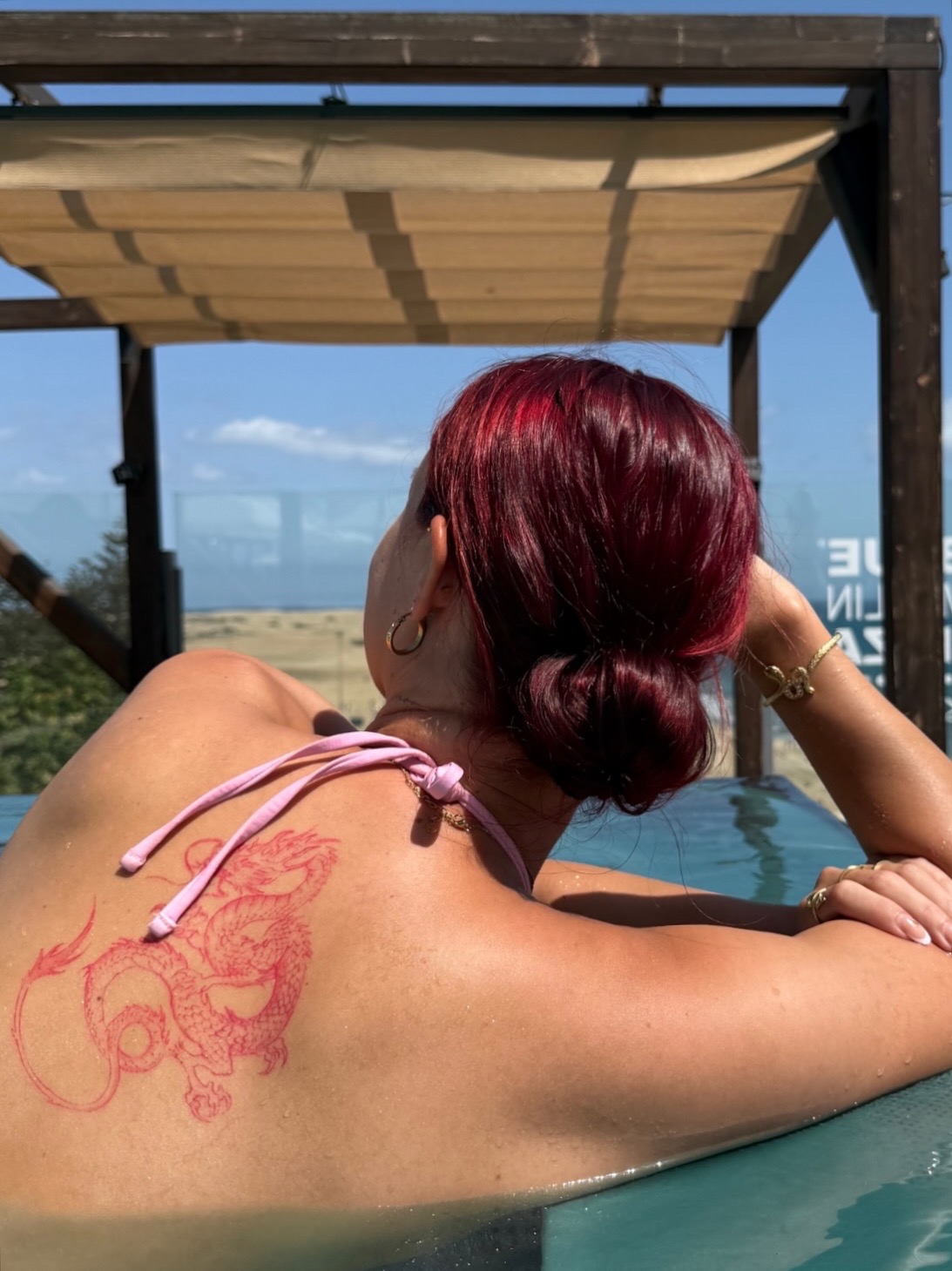 Red dragon back tattoo at a poolside overlooking the sea