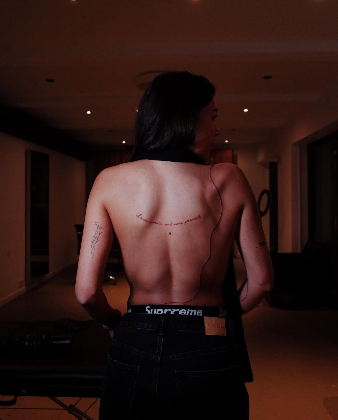 Fine line script traced along a woman's spine